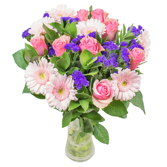 Displayed against a pristine white backdrop, this vibrant arrangement from a Barnet florist captures effortless elegance and celebration. At the heart are seven to nine perfectly arranged pink roses-some tightly coiled, others just opening, each revealing a classic spiral center augmented by subtle blush highlights. Interlaced among them are five to seven pale pink Gerbera daisies, distinguishable by their large, dainty faces and radiating pastel petals with softly fading, creamy centers. Pops of vivid purple statice weave throughout the bouquet, adding lively visual texture and depth. Plush, dark green foliage envelopes the base, suggesting the bounty of nature found in the parks of East Barnet. The bouquet rests in a clear glass vase, with freshly cut stems partially submerged in water, underscoring the arrangement's freshness and inviting a natural, uplifting presence. This bouquet, ideal for occasions such as birthdays, anniversaries, Mother's Day, or as a caring gesture for colleagues or loved ones in Barnet, reflects joy, affection, and local floral artistry from studios near The Spires and Chipping Barnet High Street.