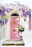 Here, a tranquil Barnet doorway is captured at the precise moment it feels ready to welcome its very first guests. The front door, painted a warm, milky pink, stands slightly recessed within a whitewashed wall, giving the entrance a sheltered, almost cocoon-like feeling. Above, generous clusters of wisteria tumble down in shades of lavender and soft mauve, each delicate bloom layering over the next to create a dreamy canopy that softens the architectural lines. The petals seem almost weightless, but they gather densely enough to cast gentle shadows and suggest that sweet, familiar scent you might notice while walking along a quiet lane near Hadley Wood. Just in front of the door, set neatly on the step, a compact metal bucket in muted grey overflows with white and creamy roses, their tightly packed heads forming a rounded, luxurious mound. The roses appear freshly cut and cool to the touch, framed by small sprays of pale green foliage that add a subtle, natural movement to the arrangement. A soft pink ribbon is tied carefully around the base of the bucket, its bow simple yet tender, echoing the colour of the door without overwhelming it. Light glows softly across the stone threshold, evoking a calm afternoon when removal boxes are stacked inside and neighbours in Barnet are starting to say hello. The composition feels both intimate and hopeful, the kind of floral gesture chosen to mark a new address with grace and understatement, turning an empty doorway into a place that already feels like home.